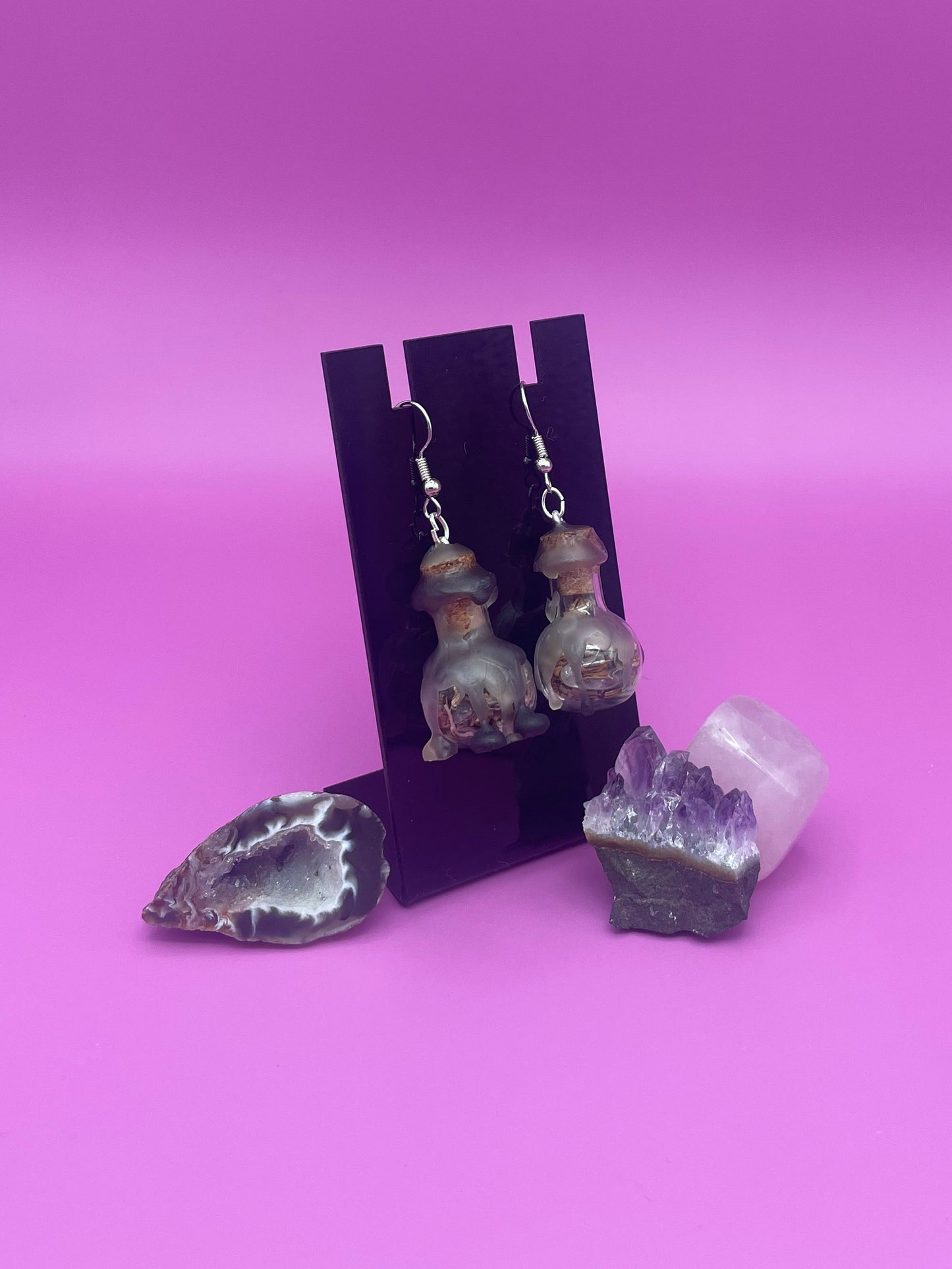 Protection spell earring on black stand with purple background 
