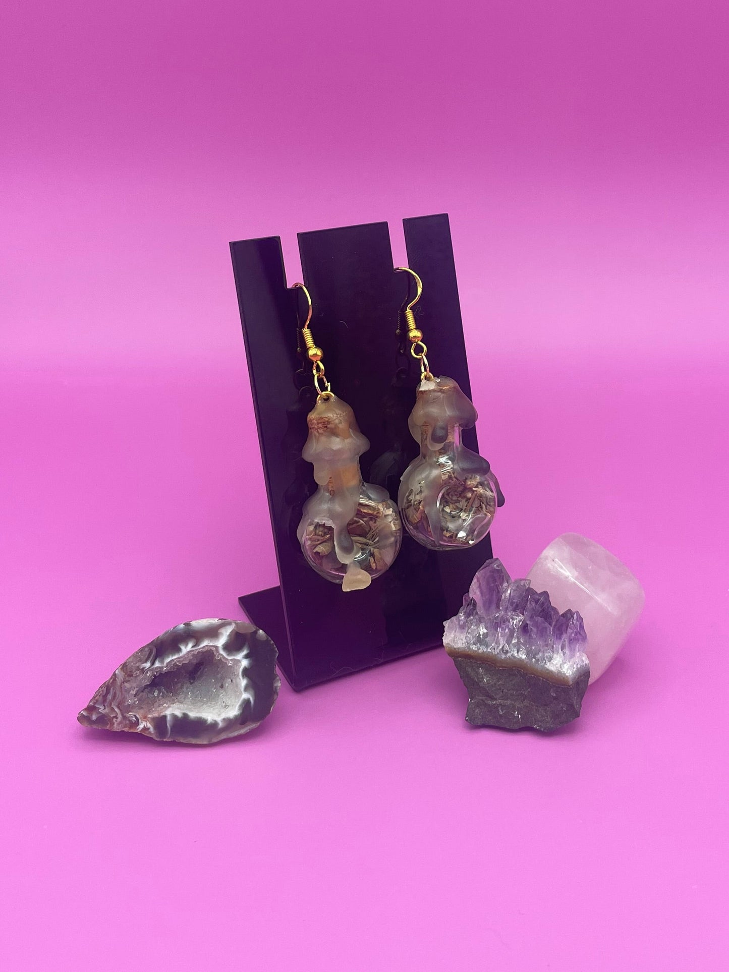 Protection spell earring on black stand with purple background 