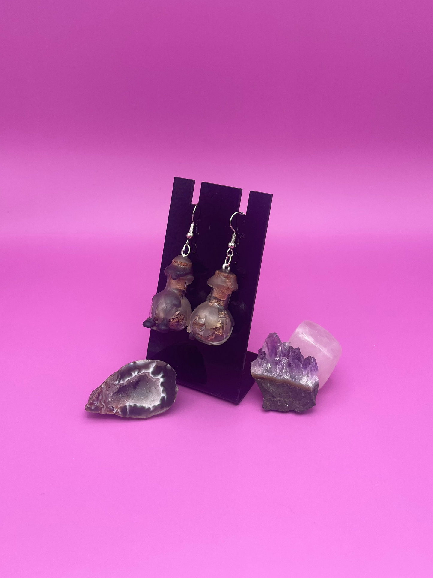 protective spell earrings on black stand with purple background 